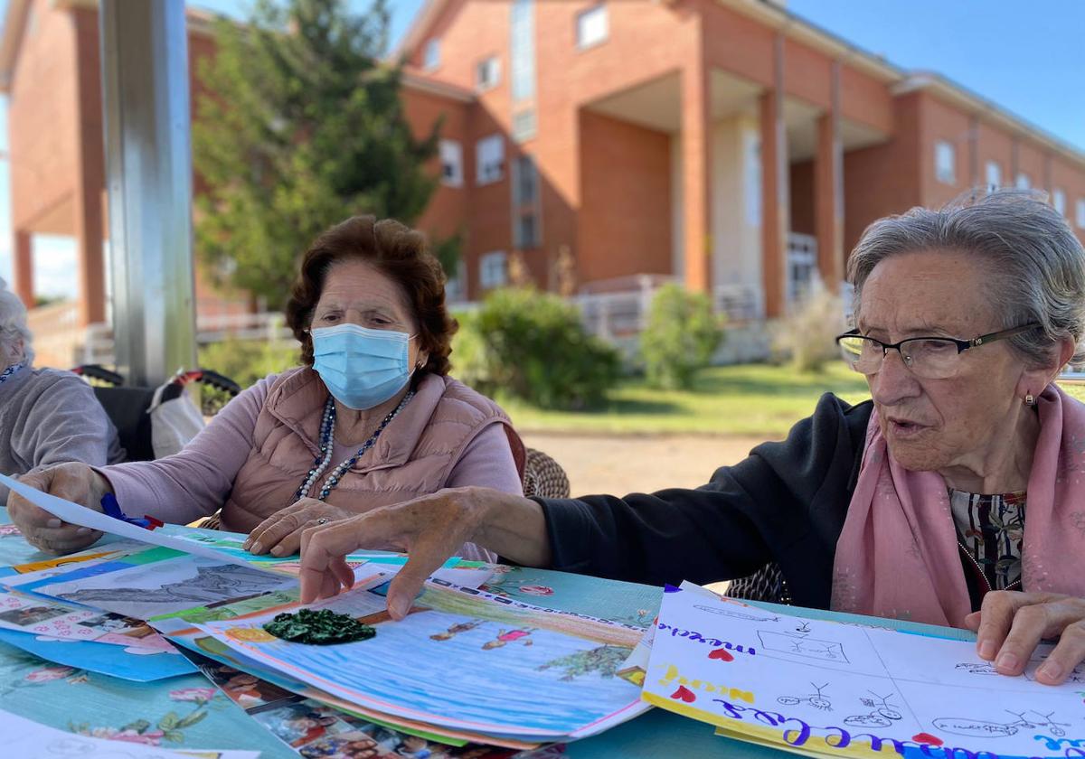 Usuarias del centro de Valdelafuente contemplan los dibujos realizados en el certamen.