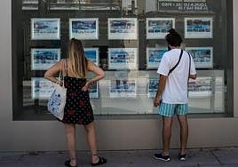 Dos personas revisan las opciones de alquiler de una inmobiliaria.