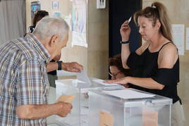 Una hombre depositando su voto en la urna.