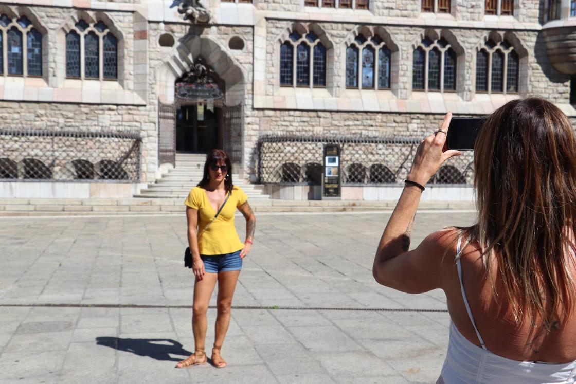 Una turista fotografía a otra con la Casa Botines de fondo.