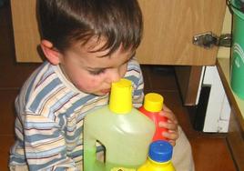 Un niño con varios productos de limpieza.