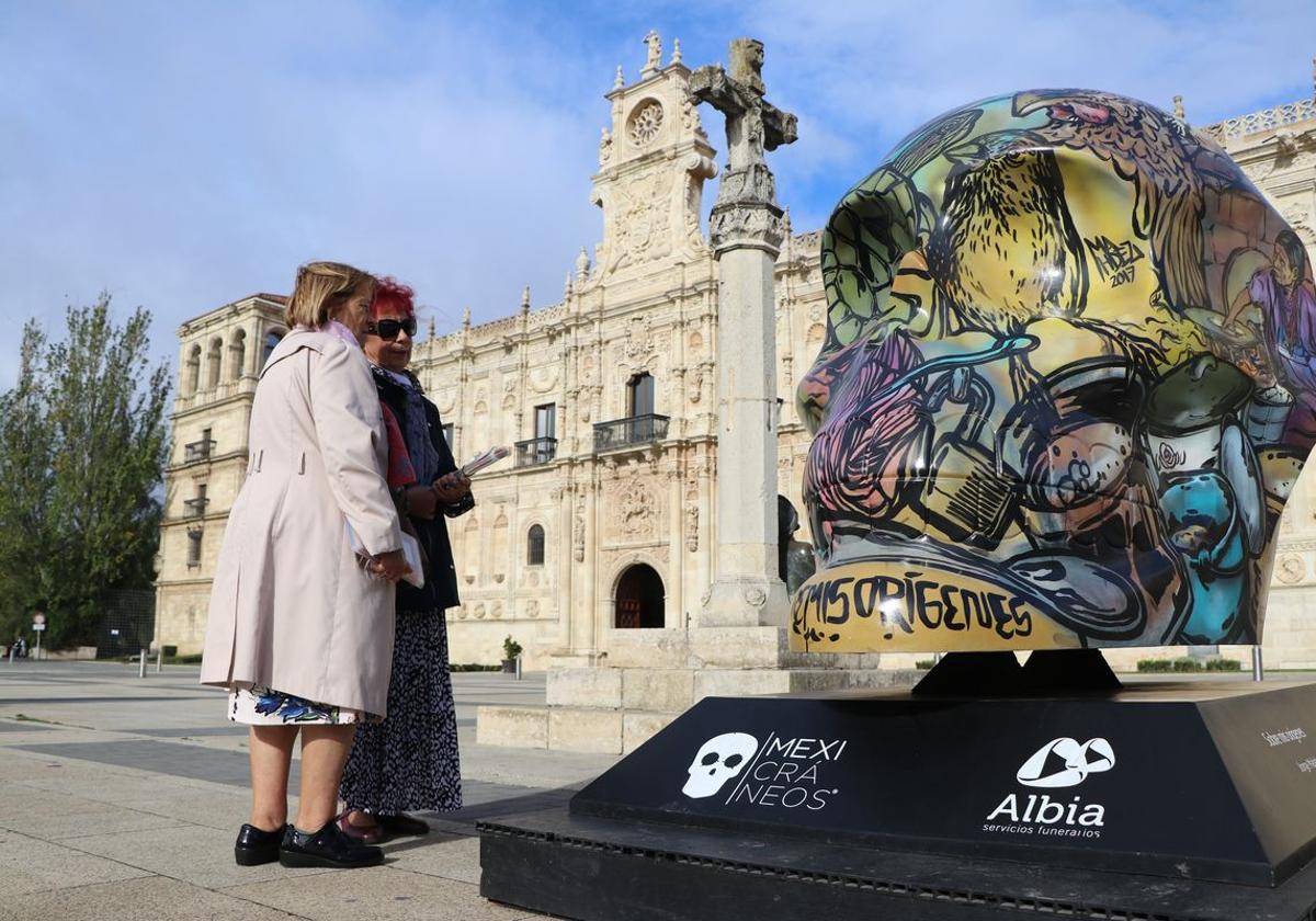 Dos mujeres observan una de las cabezas gigantes que componen la exposición 'Mexicráneos' en la plaza de San Marcos.