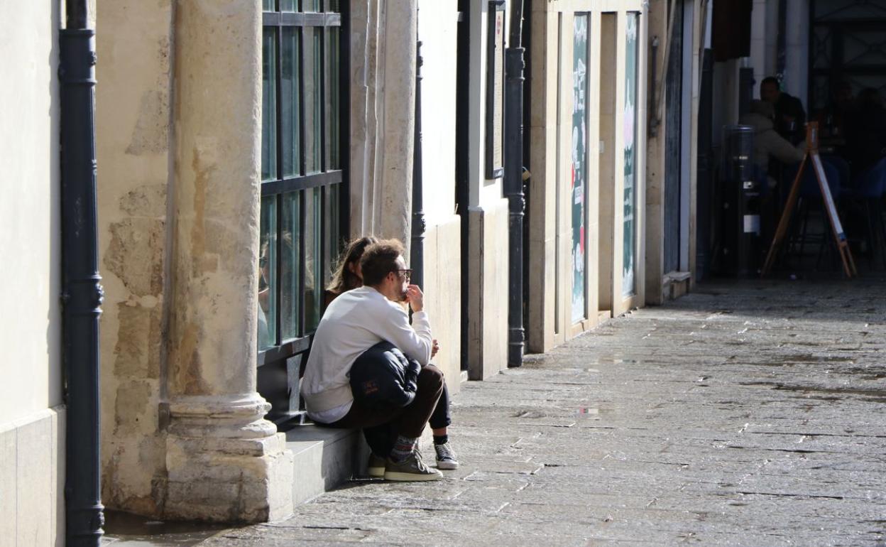 Una pareja de jóvenes sentados a las puertas de un bar en León capital.