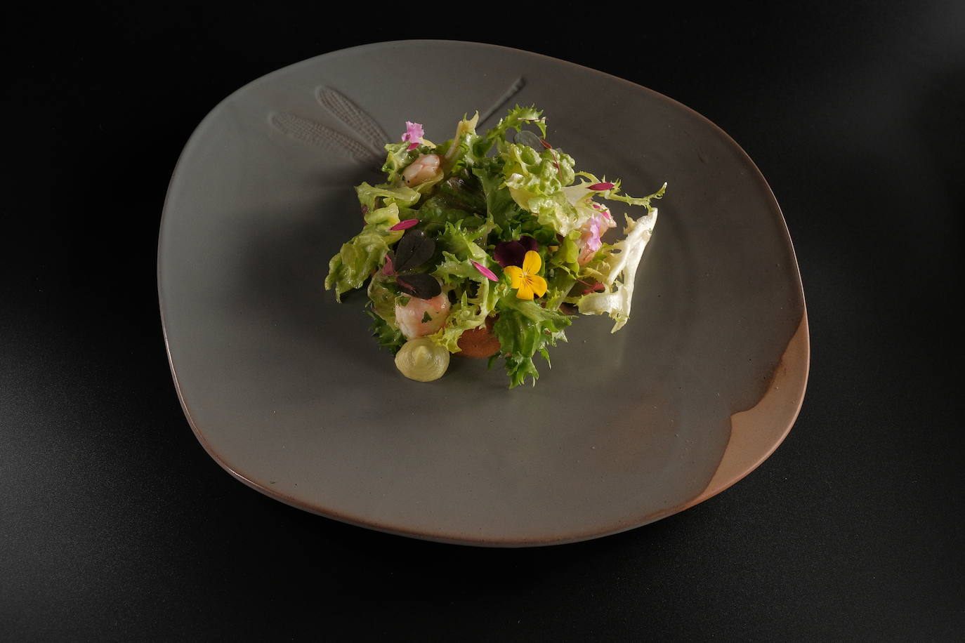 Ensalada con langostinos acevichados, vinagreta de lulo, semicurados en aceite, tomate de árbol y hojas verdes.