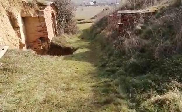 Imagen del enorme socavón provocado en el camino por el hundimiento de la bodega. 