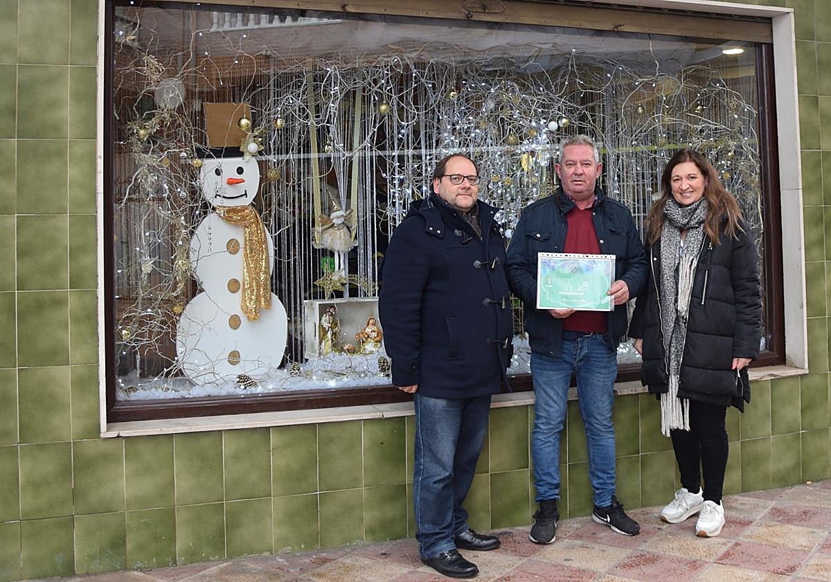 El ganador del primer premio posa frente al escaparate de su tienda.