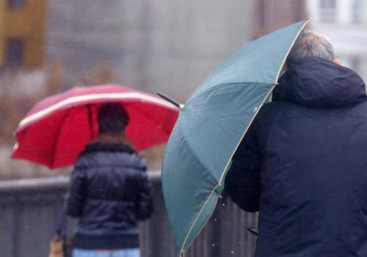 Imagen de archivo de un hombre protegiéndose del viento y la lluvia.