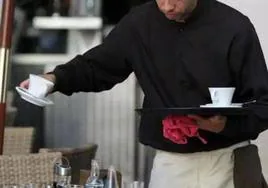 Un camarero atiende a dos comensales.