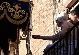 Una mujer trata de tocar el palio de una virgen durante la pasada Semana Santa.