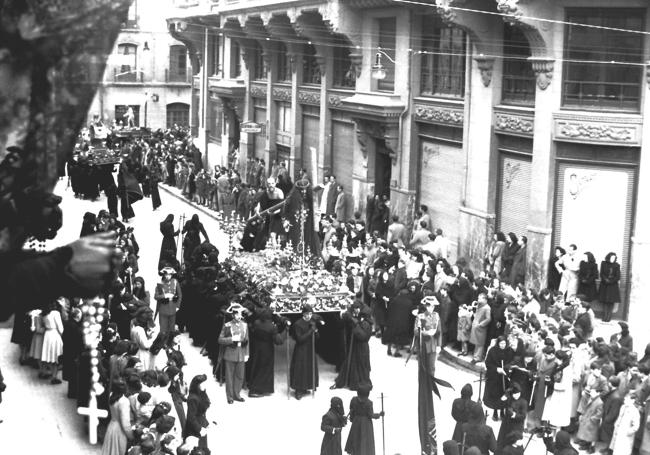 Mujer asomada al balcón con un crucifijo en la mano. Legión VII durante procesión de Viernes Santo. León