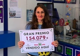 La gerente de la administración de loterías de San Andrés que selló el boleto premiado, con el cartel de la cantidad galardonada.