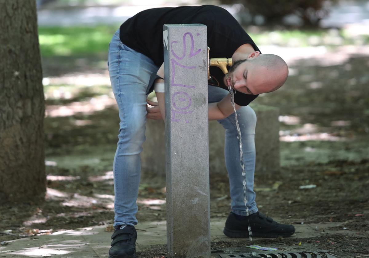 Un joven bebe agua en una fuente pública de Palencia.