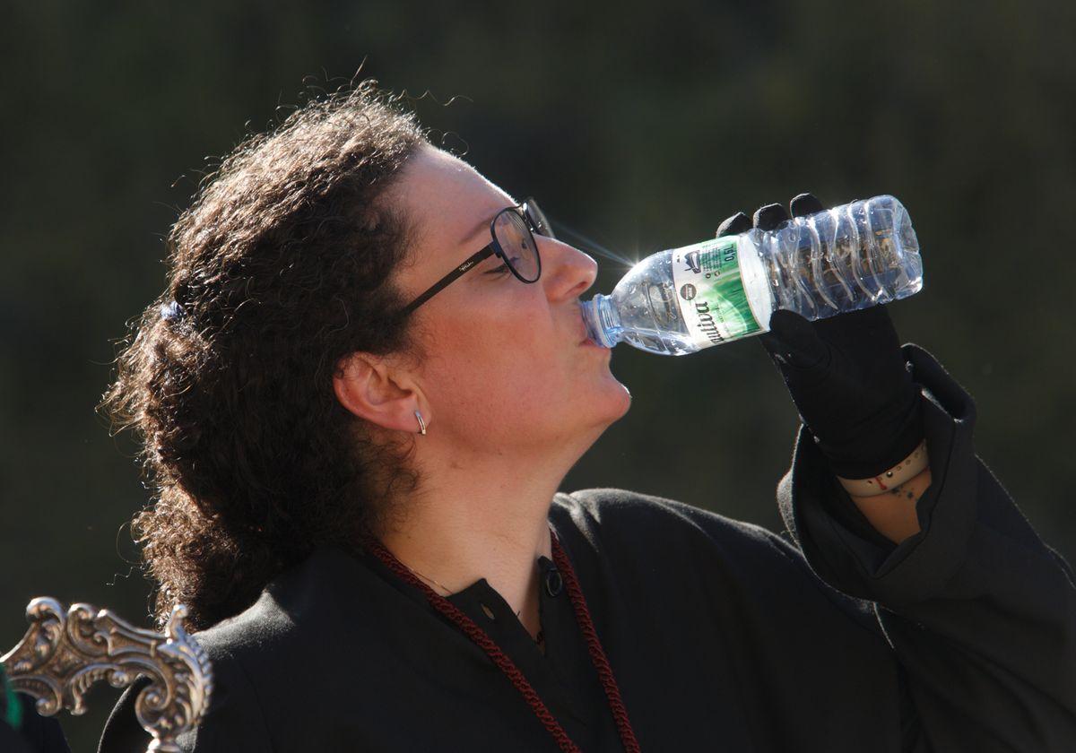 Una mujer bebe agua durante una procesión en Ponferrada