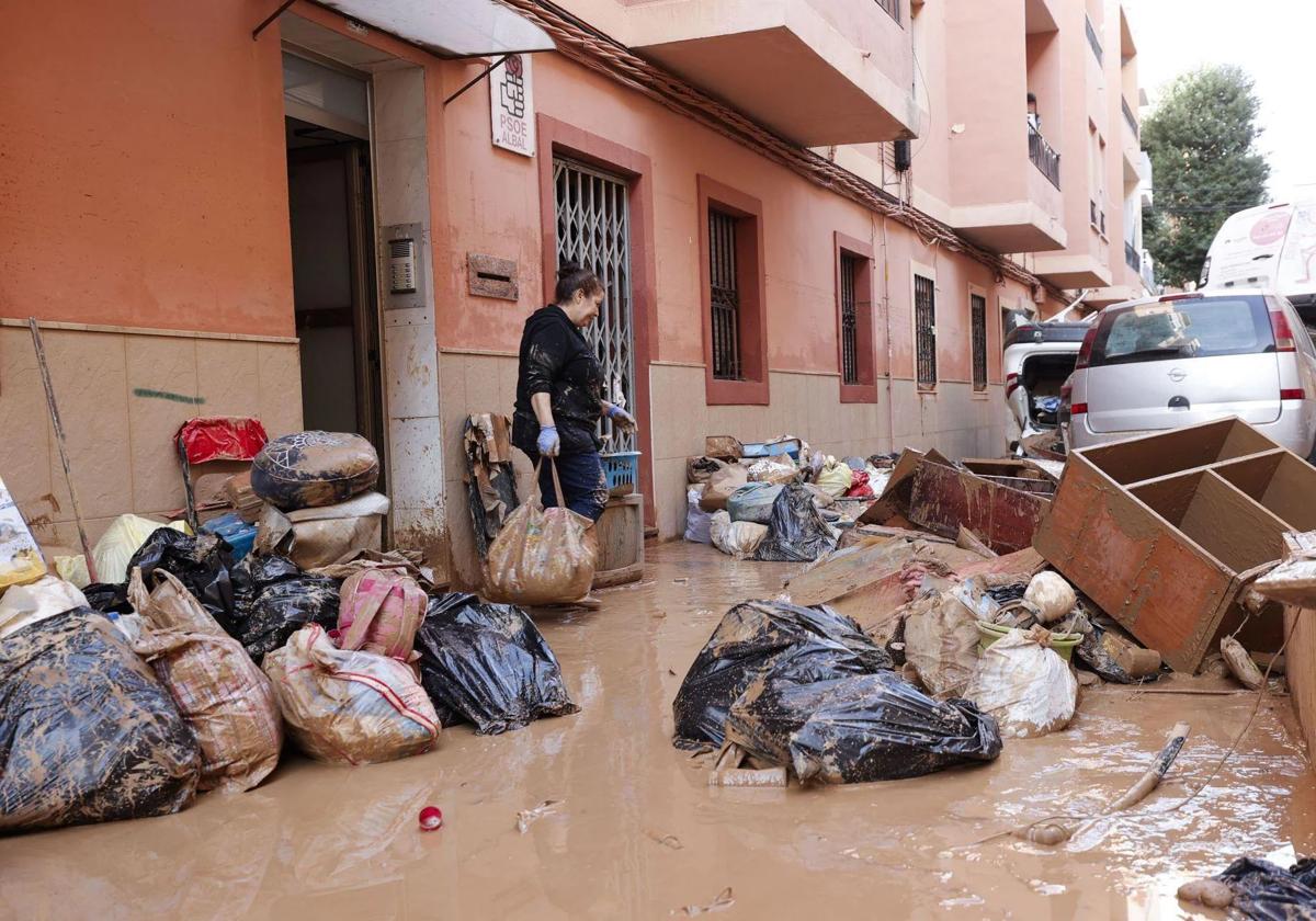 Una mujer saca de su vivienda sus pertenecias tras las intensas lluvias caídas por la fuerte DANA, este jueves en Catarroja, Valencia.