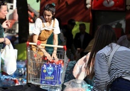 Una joven introduce agua embotellada en un carro de la compra.