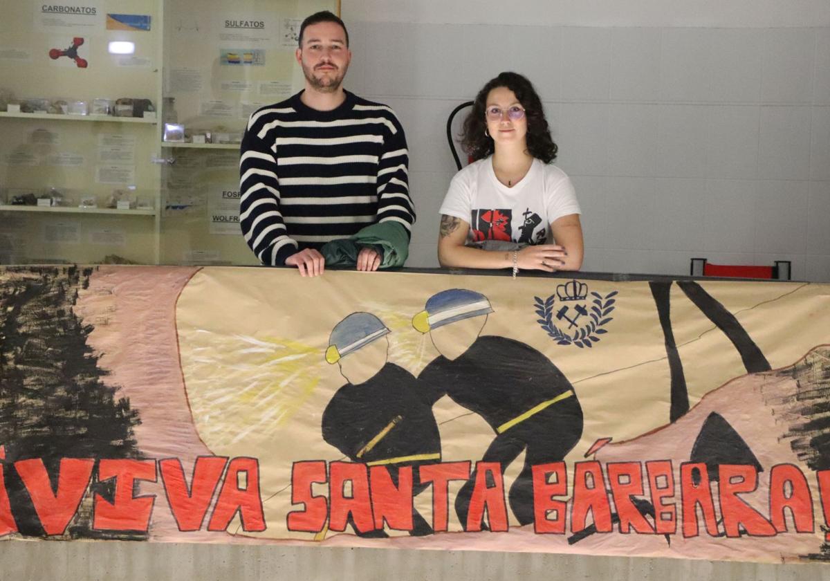 David Tornero y Paula Fernández posan junto a una pancarta que honra a la patrona de los mineros, Santa Bárbara, en la Escuela de Minas de la Universidad de León.