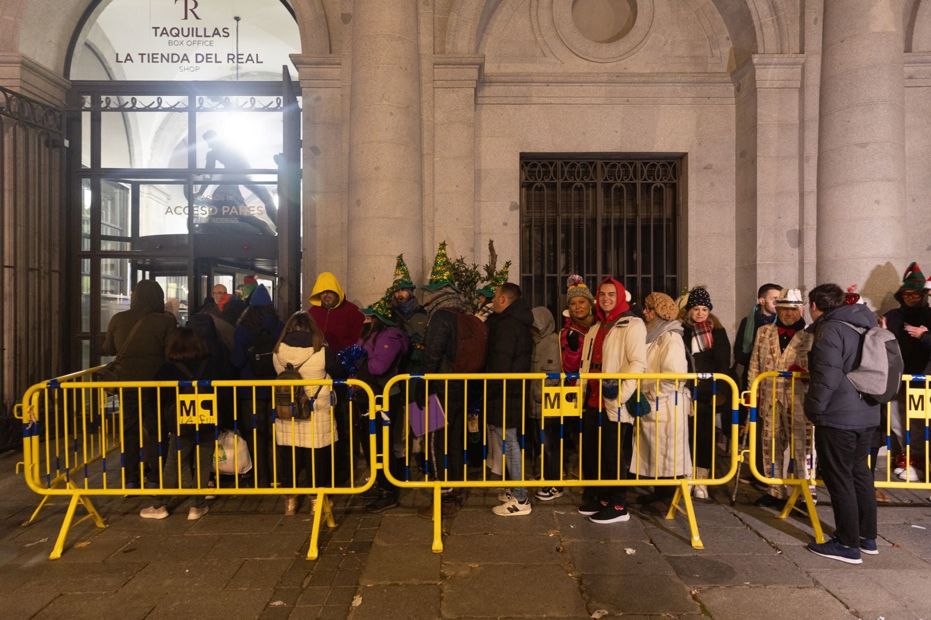 Varias personas disfrazadas antes de comenzar la celebración del Sorteo Extraordinario de la Lotería hacen cola a la entrada del Teatro Real. 