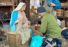 Un hombre coloca la cabeza sobre la figura del niño Jesús.