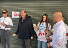 El lotero, en medio de la escena, comiendo roscón.