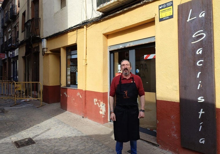 Marcelino, dueño del bar la Sacristía, en la puerta de su local junto al edificio de calle Herreros que ha provocado su corte.