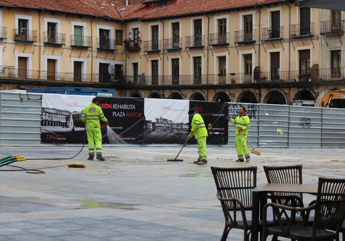 Unos trabajadores rematan el suelo de la parte de la Plaza Mayor de León que ya luce su nuevo pavimento.