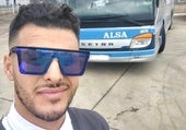 Zakaria junto a un autobús de su compañía.