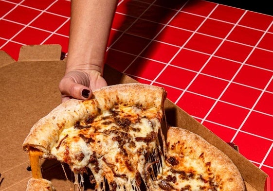 Una usuaria toma un pedazo de pizza.