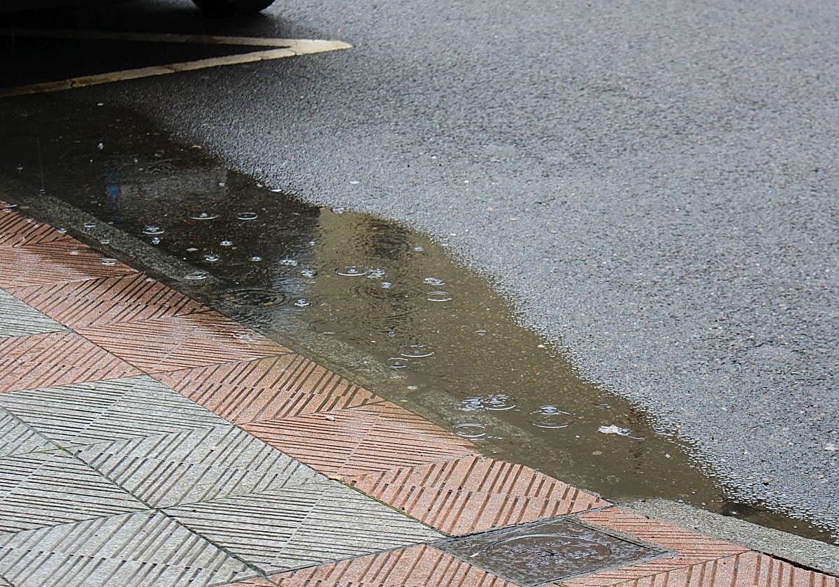 Lluvia ligera sobre un charco en una calle de León.