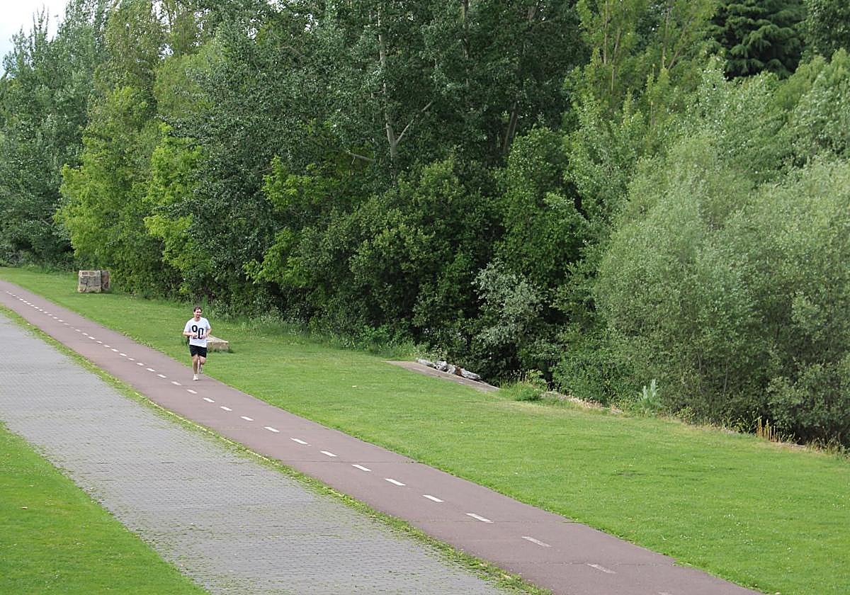Un joven realiza deporte a orillas del río Bernesga a su paso por León capital.