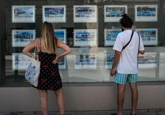 Dos personas revisan las opciones de alquiler de una inmobiliaria.