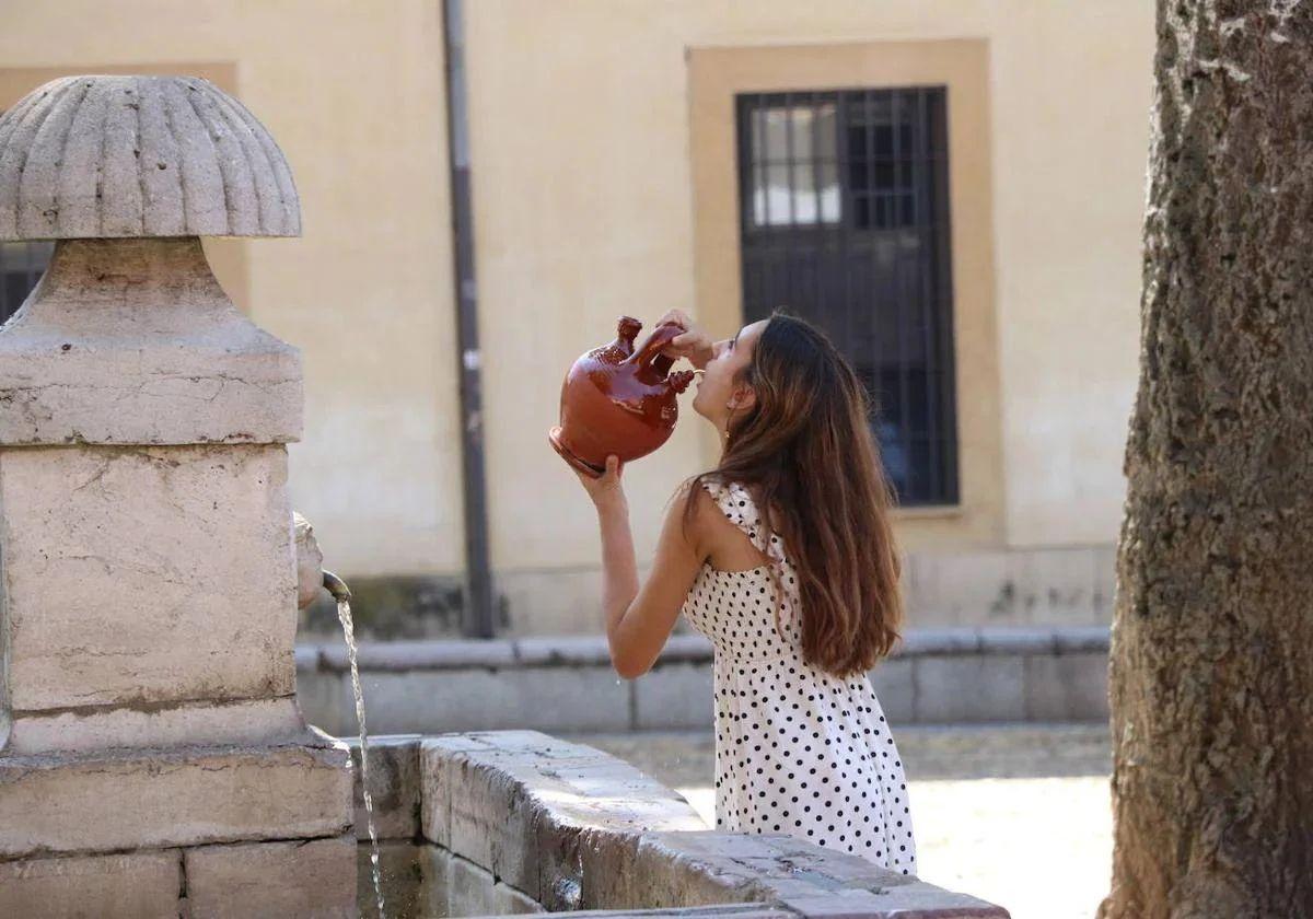 Una mujer bebe de una fuente en León.