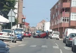 Un coche volcado corta un carril en una calle de Trobajo del Camino.