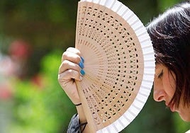 Una mujer se protege del sol con su abanico.