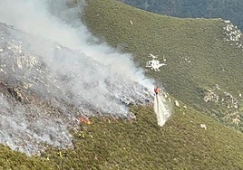 Un helicóptero descarga agua sobre el fuego en el incendio de Llamas de Cabrera