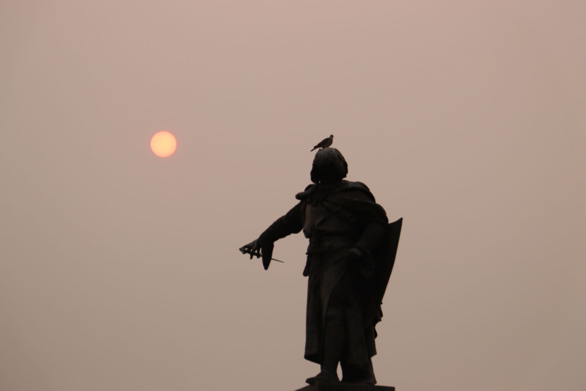 El sol enrojecido en la tarde del lunes 18 de agosto tras la estatua de Guzmán el Bueno en León.