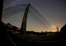Una espectacular vista del puente de Barrios de Luna y el cielo estrellado durante un atardecer.