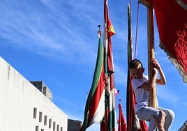 Un niño trepa por uno de los pendones del desfile de la romería de San Froilán.