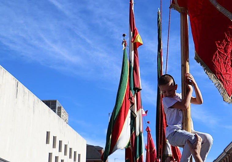 Un niño trepa por uno de los pendones del desfile de la romería de San Froilán.
