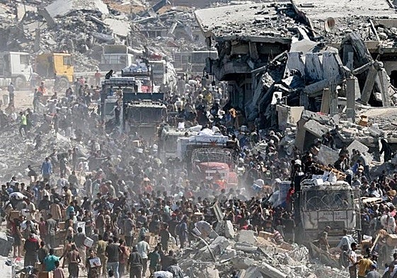 Cientos de palestinos recogen ayuda humanitaria de camiones que han ingresado a Gaza.