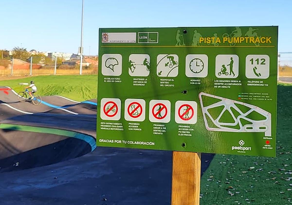 Imagen principal - Cartel con las obligaciones de los usuarios; marca que anuncia la colocación de un dispositivo de alumbrado; y una flecha roja que indica la dirección y la dificultad -avanzada- de esta parte de la pista de pumptrack en Puente Castro.