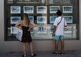 Dos personas, fijándose en pisos de una inmobiliaria.