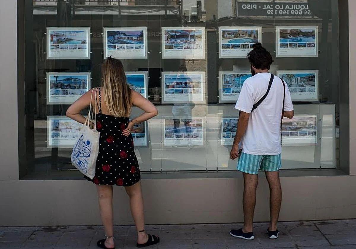 Dos personas, fijándose en pisos de una inmobiliaria.