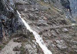 Cascada formada por la rotura de un canal sobre la senda.