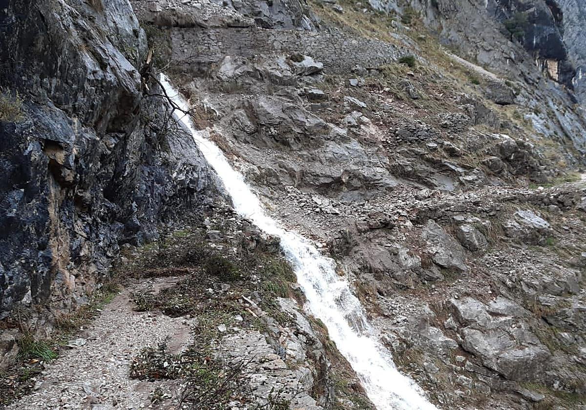 Cascada formada por la rotura de un canal sobre la senda.