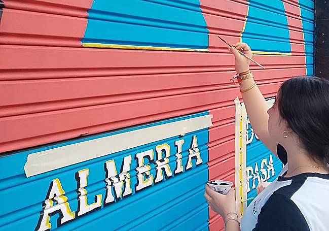 Una alumna del Maristas pintando el mural.