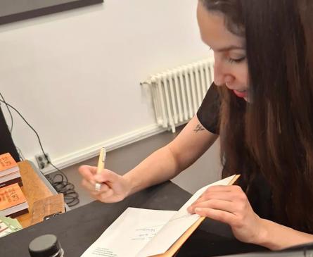 Imagen secundaria 1 - Mónica Ágreda con dos gatos, firmando libros y la portada de su libro.
