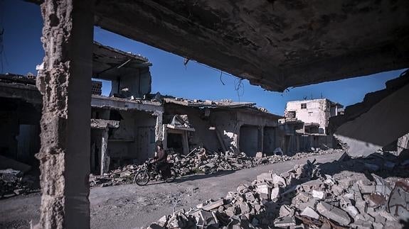 Un hombre circula en moto por las calles destruidas de Duma, en las afueras de Damasco, Siria.