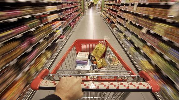 Una persona empuja un carrito por un pasillo de supermercado.