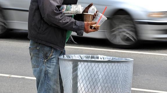 Un hombre buscando comida entre la basura. 