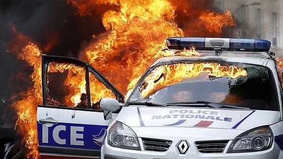 Manifestantes prenden fuego un coche de la policía en París. 